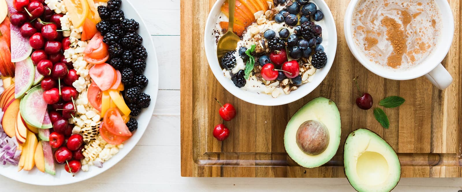 Frisches Obst, Joghurtschale und Kaffee auf einem Holzbrett
