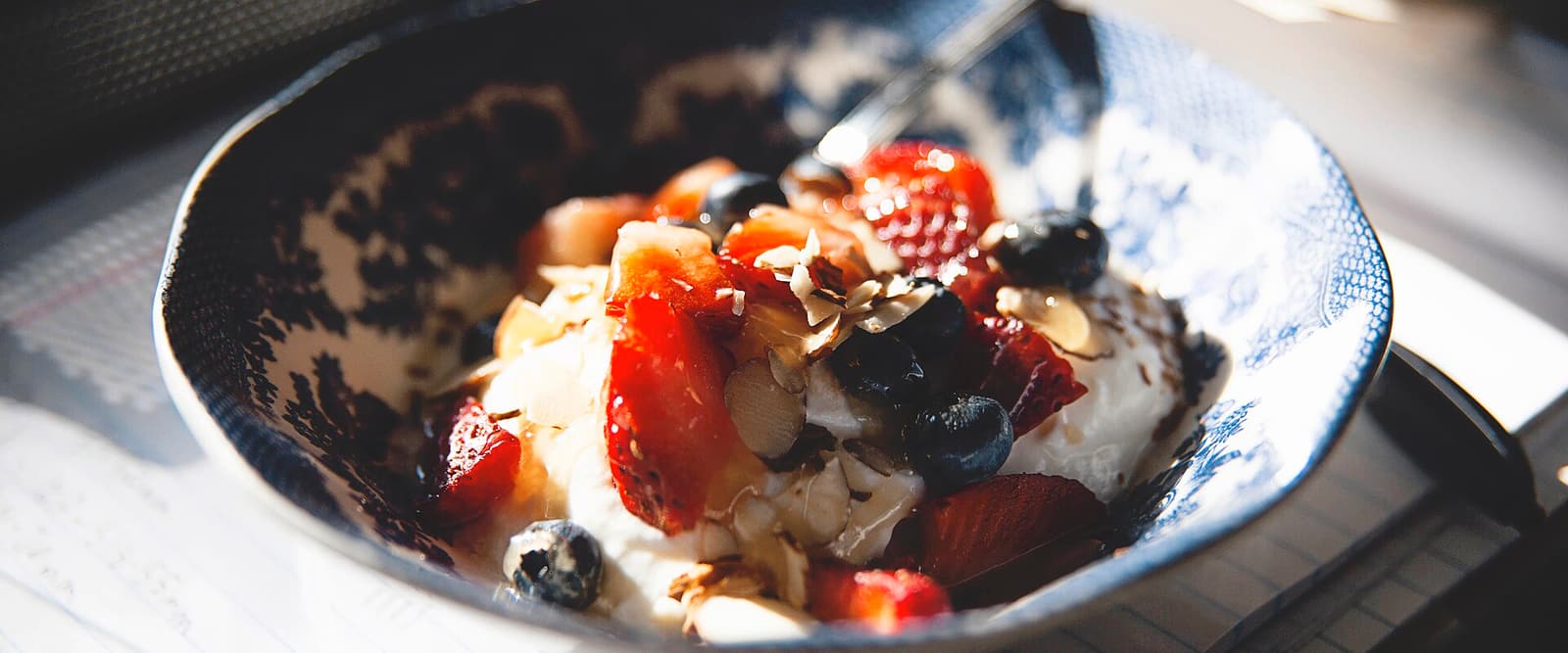 Schale mit Joghurt, Beeren und Nüssen auf einem Tisch