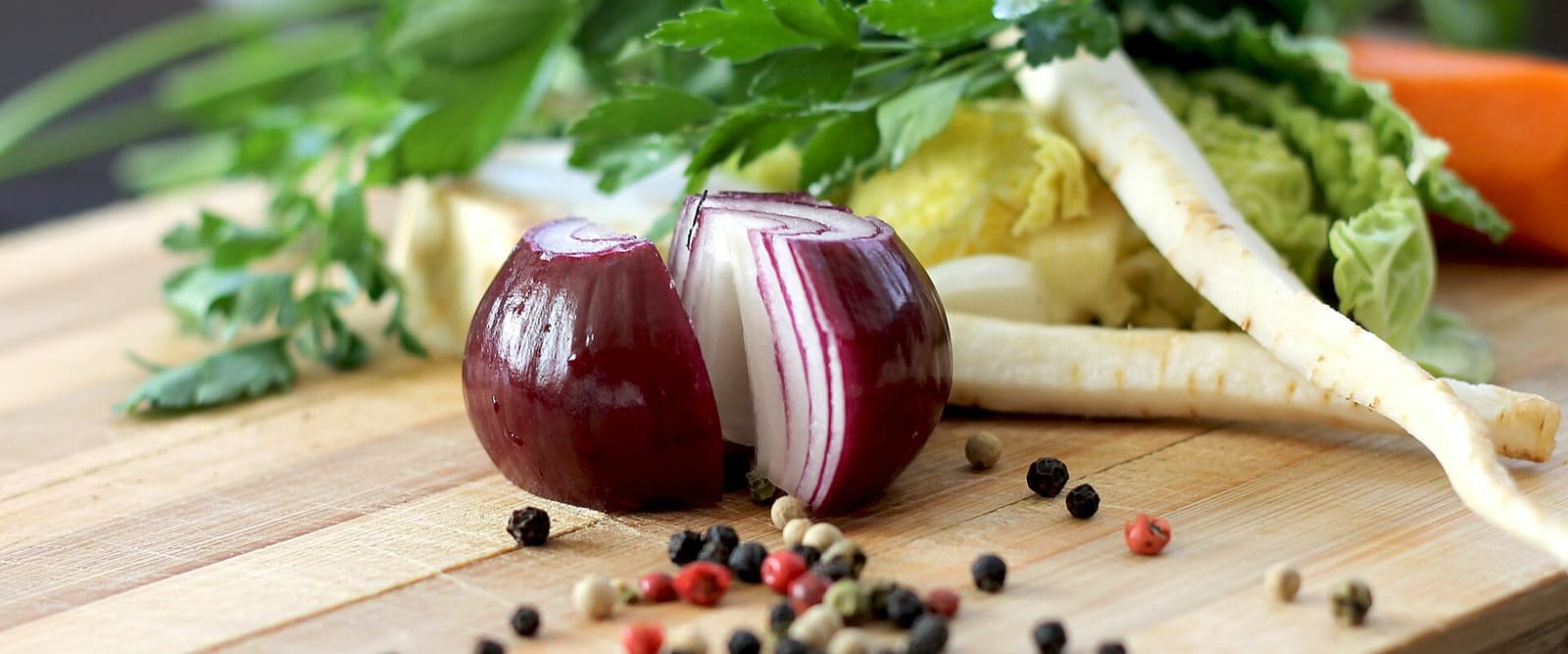 Zwiebel und frisches Gemüse auf einem Holzbrett